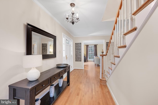 entrance foyer with a notable chandelier, stairway, light wood-style floors, crown molding, and baseboards