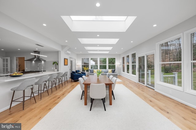 dining area featuring a wealth of natural light, light wood-type flooring, and a skylight