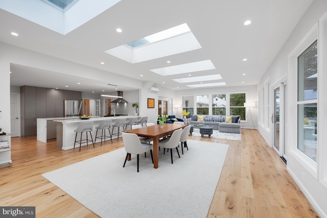 dining area with recessed lighting, a skylight, light wood-type flooring, and baseboards