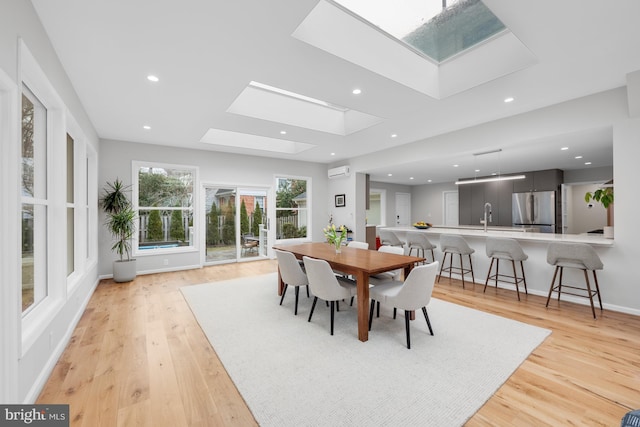 dining area featuring recessed lighting, an AC wall unit, a skylight, and light wood finished floors