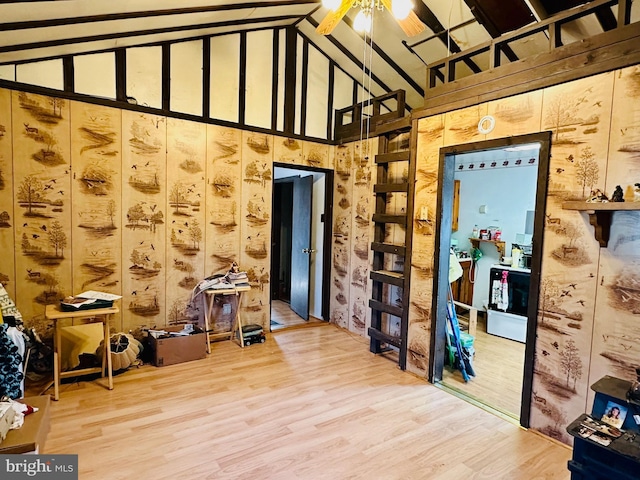 interior space featuring ceiling fan, high vaulted ceiling, and wood finished floors