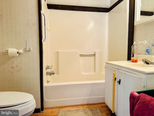 full bathroom featuring toilet, wood finished floors, tile walls,  shower combination, and vanity