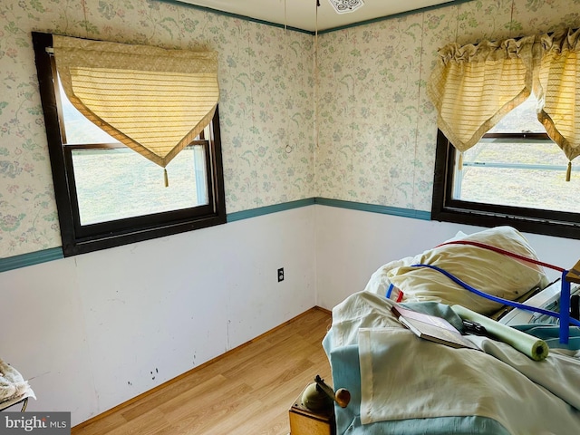 sitting room with wood finished floors, wainscoting, and wallpapered walls