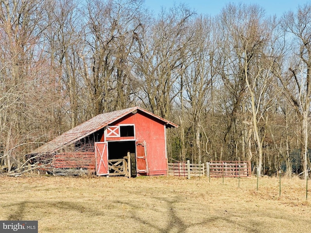 view of outbuilding with an outbuilding, fence, and a forest view