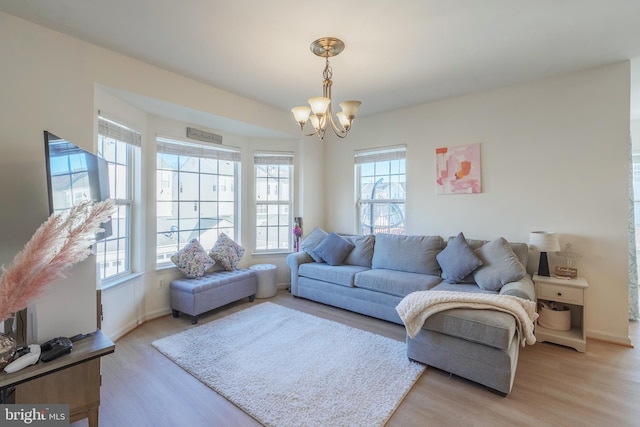 living room with an inviting chandelier, baseboards, and light wood finished floors