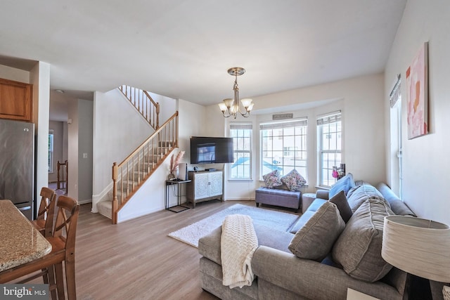 living area with light wood-type flooring, stairway, baseboards, and a chandelier