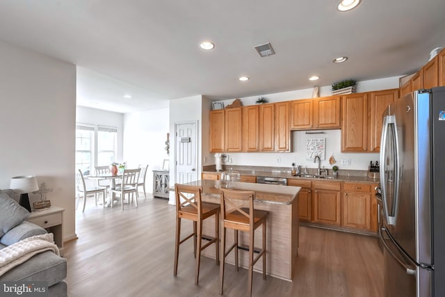 kitchen with visible vents, open floor plan, appliances with stainless steel finishes, wood finished floors, and a sink