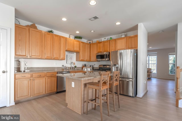 kitchen with visible vents, light wood finished floors, a sink, stainless steel appliances, and a center island