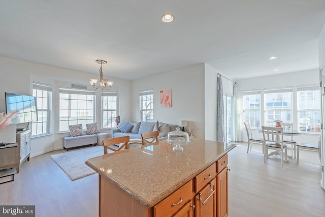 kitchen featuring light stone counters, open floor plan, recessed lighting, light wood-style floors, and an inviting chandelier