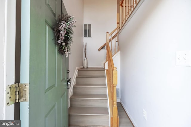 stairway with wood finished floors, visible vents, and baseboards