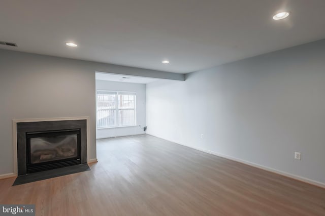 unfurnished living room featuring recessed lighting, a fireplace with flush hearth, wood finished floors, and visible vents