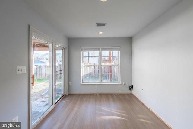 unfurnished room featuring a wealth of natural light, visible vents, and wood finished floors