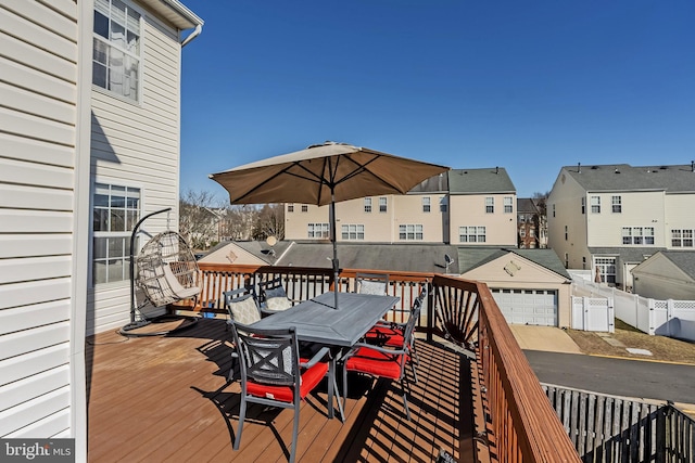 deck featuring a detached garage, fence, a residential view, an outbuilding, and outdoor dining space