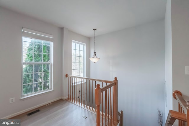 staircase featuring plenty of natural light, wood finished floors, visible vents, and baseboards