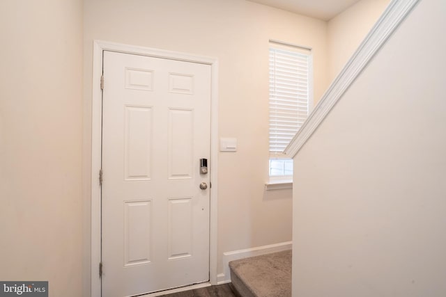 foyer entrance with stairway and baseboards