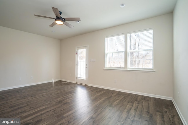 unfurnished room featuring dark wood-type flooring, plenty of natural light, and baseboards