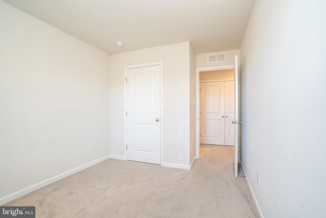 unfurnished bedroom featuring light colored carpet, visible vents, and baseboards