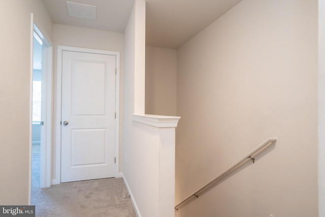 hall featuring an upstairs landing, visible vents, carpet floors, and baseboards