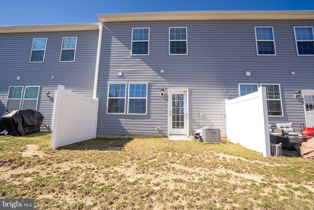 rear view of house featuring a yard, central AC, and fence