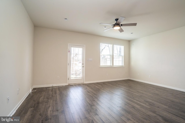 empty room featuring baseboards, dark wood-type flooring, and a ceiling fan