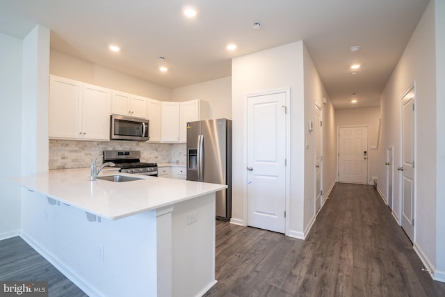 kitchen with backsplash, white cabinetry, appliances with stainless steel finishes, a peninsula, and light countertops