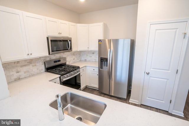 kitchen featuring a sink, decorative backsplash, light countertops, stainless steel appliances, and white cabinetry