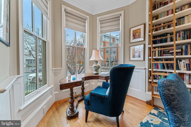 office area featuring a wainscoted wall, light wood-style floors, and crown molding