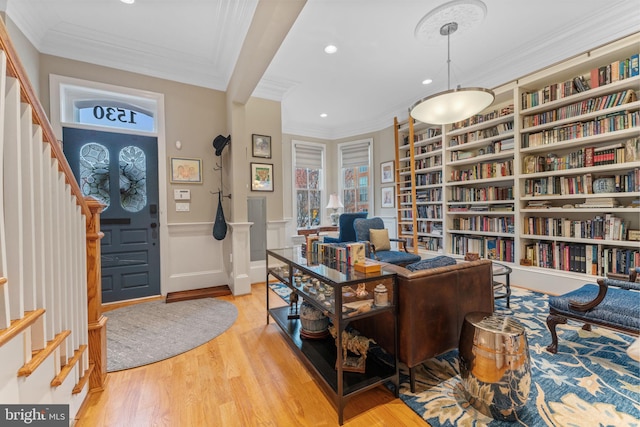 office space featuring built in shelves, wood finished floors, recessed lighting, wall of books, and crown molding