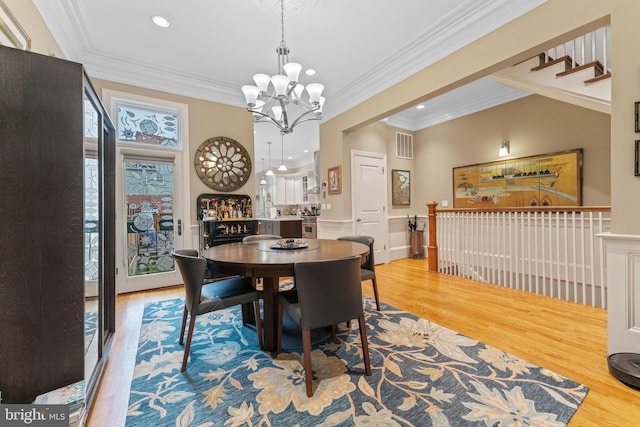 dining space featuring visible vents, a notable chandelier, ornamental molding, wood finished floors, and recessed lighting