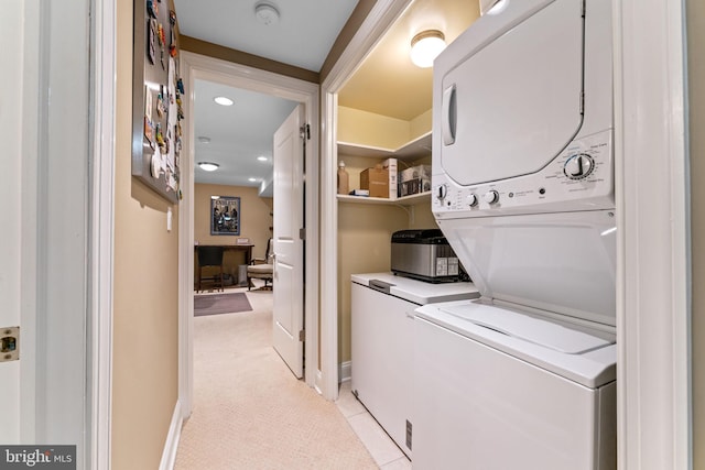 washroom with baseboards, light colored carpet, stacked washer and dryer, light tile patterned floors, and laundry area