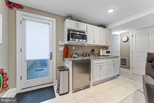 kitchen featuring light tile patterned floors, stainless steel microwave, white cabinets, and high end refrigerator