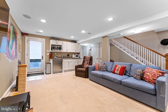 living area with recessed lighting, stairway, light tile patterned floors, baseboards, and light colored carpet