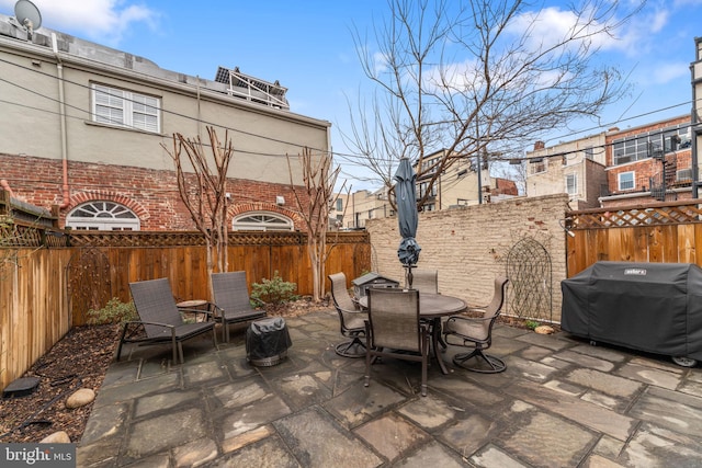 view of patio with area for grilling, outdoor dining space, and a fenced backyard