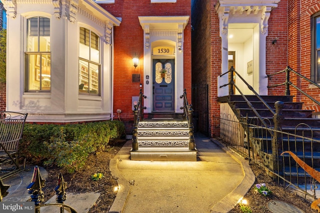 property entrance featuring fence and brick siding