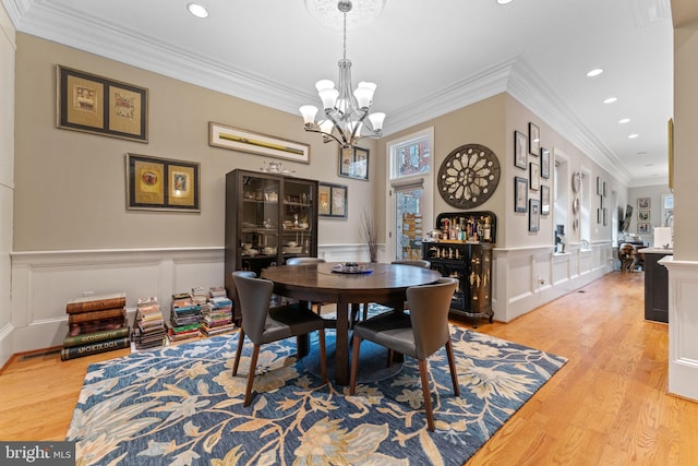 dining space featuring recessed lighting, a wainscoted wall, an inviting chandelier, and light wood-style flooring