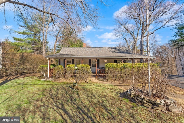 ranch-style home with covered porch, a front yard, and a shingled roof