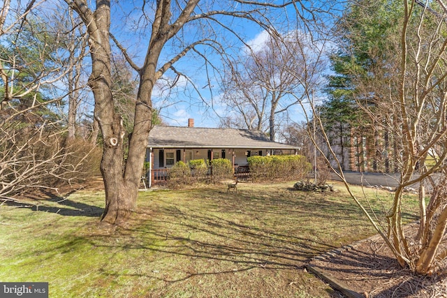 view of front of house with a front yard, covered porch, and a chimney