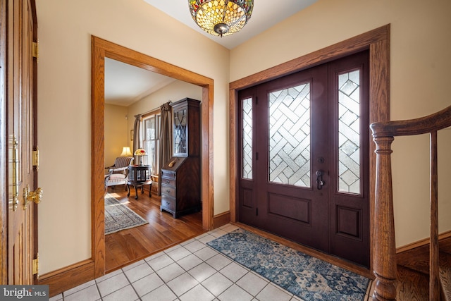 entrance foyer with light tile patterned floors, a chandelier, and baseboards