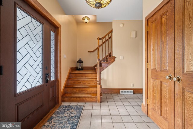 entryway with light tile patterned floors, stairway, baseboards, and visible vents