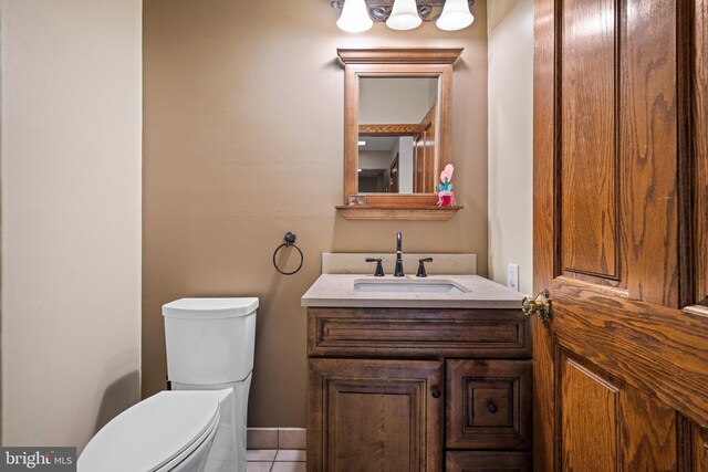 half bath with tile patterned floors, toilet, and vanity