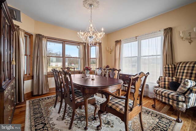 dining space featuring baseboards, an inviting chandelier, and wood finished floors