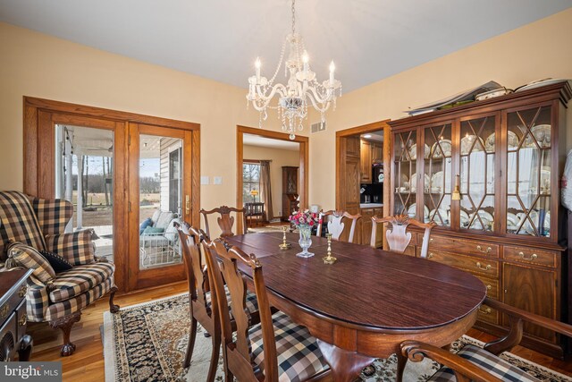 dining area featuring an inviting chandelier, light wood-style flooring, and visible vents