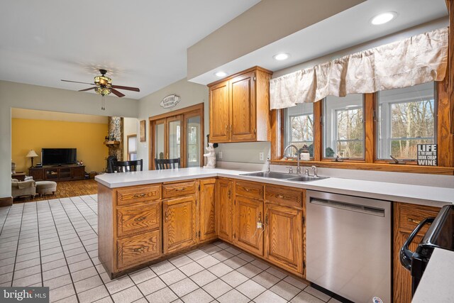 kitchen featuring dishwasher, light countertops, a peninsula, a ceiling fan, and a sink