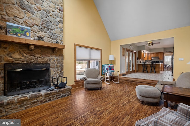 living room with high vaulted ceiling, a ceiling fan, wood finished floors, a fireplace, and baseboards