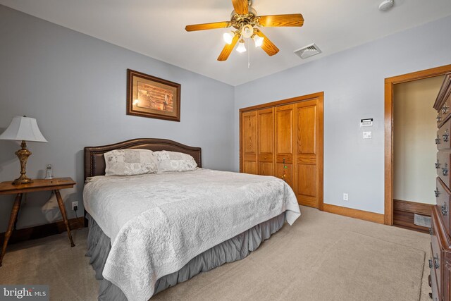 bedroom with baseboards, visible vents, ceiling fan, a closet, and light colored carpet