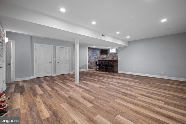 finished basement with recessed lighting, visible vents, baseboards, and wood finished floors