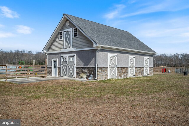 view of barn featuring a yard and fence