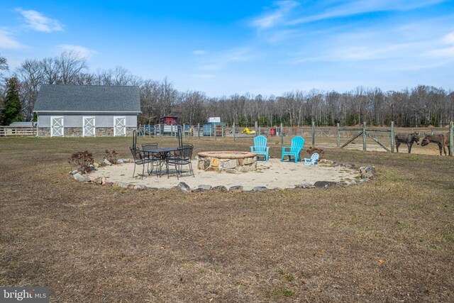 view of yard with a barn, a fire pit, an outdoor structure, and fence