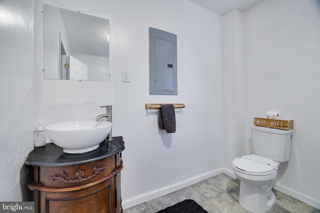 half bathroom featuring electric panel, toilet, vanity, and baseboards