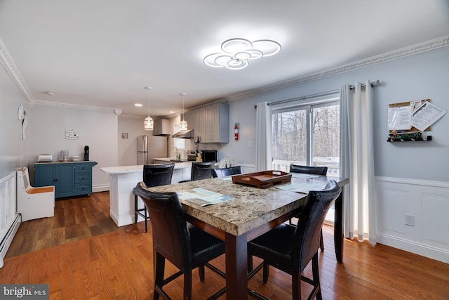 dining space featuring dark wood-style floors, wainscoting, and ornamental molding